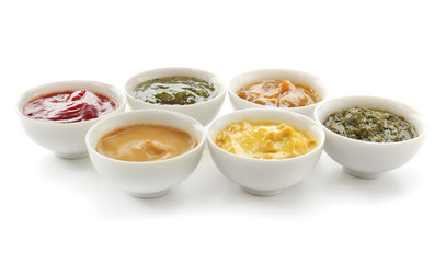 Different tasty sauces in bowls on white background