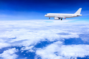 Airplane flying away in to sky high altitude above the white clouds