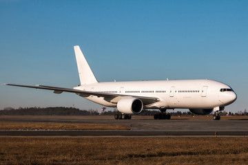 Fototapeta na wymiar White wide body passenger aircraft taxiing on the main taxiway