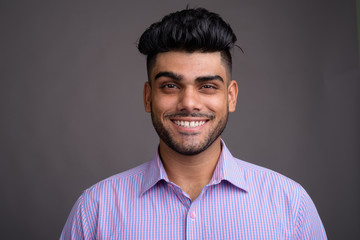 Obraz premium Young handsome Indian businessman against gray background