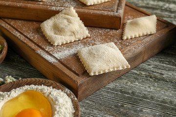 Wooden board with tasty ravioli on table, closeup