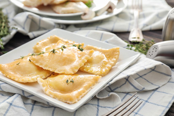 Plate with tasty ravioli on table