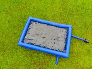 Big inflatable blue trampoline on green grass