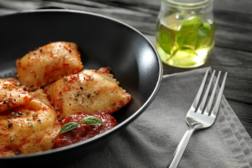 Plate with cooked ravioli on table