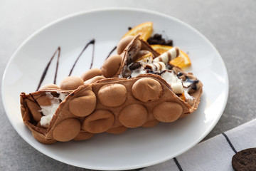 Plate with delicious sweet bubble waffle on grey table