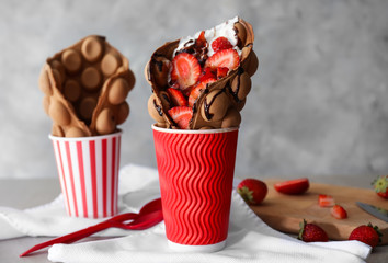 Delicious sweet bubble waffle in cup on table