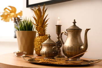 Obraz na płótnie Canvas Golden tableware on wooden table near light wall