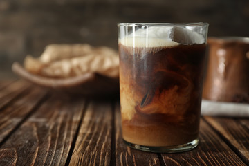 Glass of cold coffee with milk on wooden table