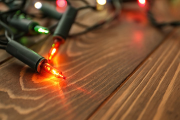 Glowing Christmas lights on wooden table, closeup
