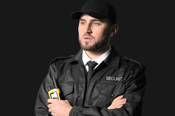 Male security guard with portable radio transmitter on dark background