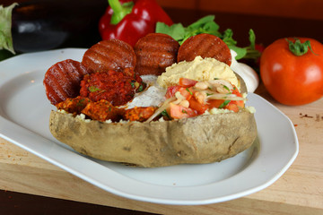 Kumpir - Traditional Turkish meal with baked potato, butter, cheese, bulgur salad, beef sausage and hot spices