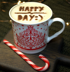 Cup of cappuccino with Christmas candy and the words happy day