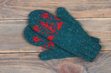 Knitted mittens in green on wooden background. Handwork. View from above.