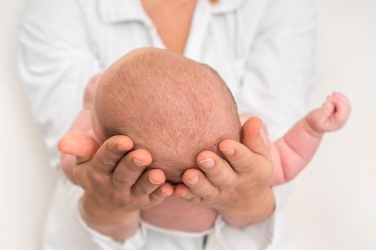 Mother Holds Head Of Newborn Baby In Her Hands