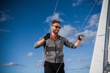 Young man lifting the sail of catamaran during cruising