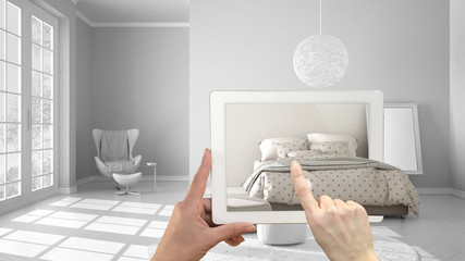 Augmented reality concept. Hand holding tablet with AR application used to simulate furniture and interior design products in real home, modern bedroom with double bed