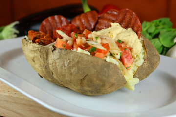 Kumpir - Traditional Turkish meal with baked potato, butter, cheese, bulgur salad, beef sausage and hot spices