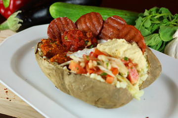 Kumpir - Traditional Turkish meal with baked potato, butter, cheese, bulgur salad, beef sausage and hot spices