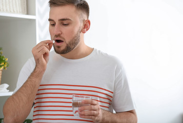 Young man ill with flu taking medicine at home