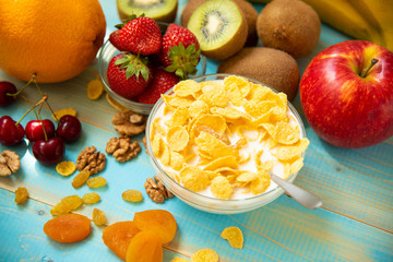 Tasty cornflakes with milk and fruits in glass bowl