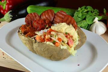 Kumpir - Traditional Turkish meal with baked potato, butter, cheese, bulgur salad, beef sausage and hot spices