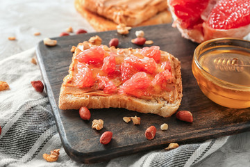 Board with sweet toast and honey on table, closeup