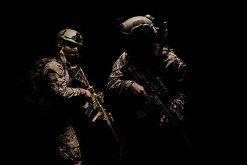 soldiers or private military contractors holding rifle. Image on a black background. war, army,...