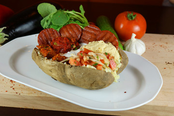 Kumpir - Traditional Turkish meal with baked potato, butter, cheese, bulgur salad, beef sausage and hot spices