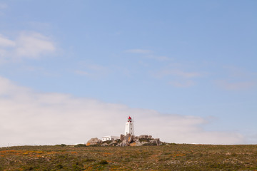 Lighthouse on a rocky hill with big misty sky, copy space