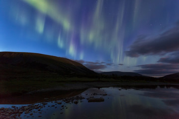 Fototapeta na wymiar Aurora in the night sky cut the mountains, reflected in the water. Yamal. Russia