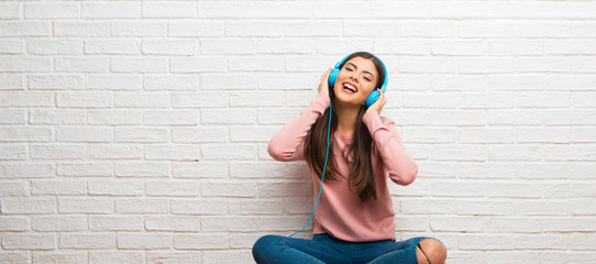 Teenager girl sitting on the floor in a room listening to music with headphones