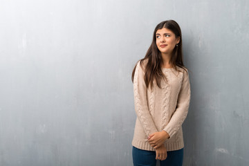 Teenager girl with sweater on a vintage wall is a little bit nervous and scared pressing the teeth