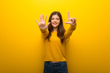 Teenager girl on vibrant yellow background counting seven with fingers