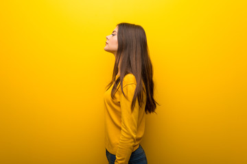 Teenager girl on vibrant yellow background in lateral position