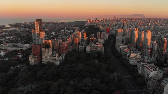 High altitude wide aerial drone view of Palermo and Recoleta Neighborhood in Buenos Aires during sunset with city park and skyscrapers buildings. Warm orange colors.