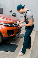 Fototapeta na wymiar auto mechanic with notepad examining car at auto repair shop