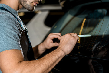 Fototapeta na wymiar partial view of auto mechanic checking car details at mechanic shop