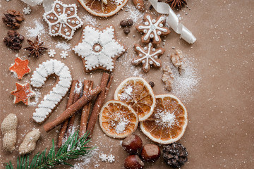 Frame with fir branches, Gingerbread cookies and Christmas decorations on dark brown paper background. Top view.