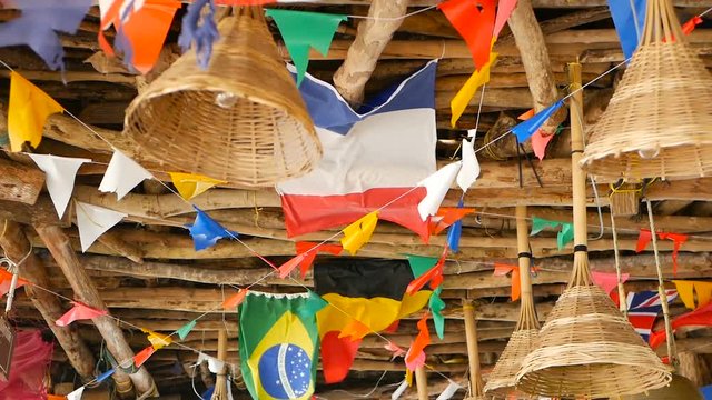 Decorative national flags of different countries hanging on strings in wooden tropical bungalow. Exotic rasta bar interior. Summer beach house on Koh Phangan island, Thailand.