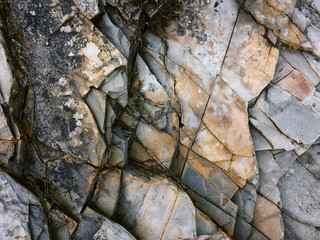 fractured rock strata as a background, cracked rock, stone texture, many cracks in the stone,...