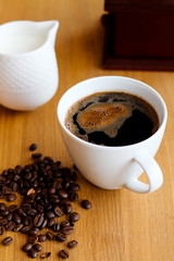 Aromatic fresh coffee in porcelain cup on wooden table