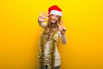 Girl celebrating the christmas holidays on yellow background counting seven with fingers