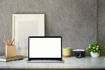 Obraz premium Creative workspace, blank screen laptop, Mockup poster and vintage camera on desk