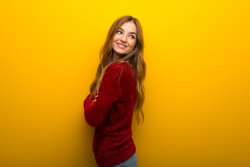 Young girl on vibrant yellow background looking over the shoulder with a smile