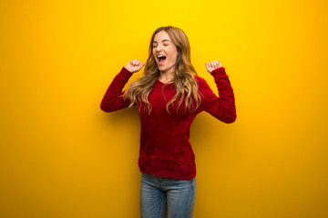 Young girl on vibrant yellow background happy and jumping