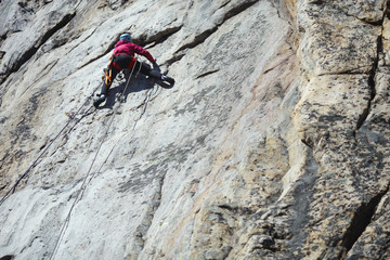 A girl climber climbs the rock wall. Competitions in rock climbing.
