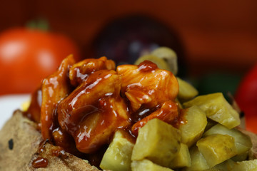 Kumpir - Traditional Turkish meal with baked potato, butter, cheese, cucumber, chicken with barbecue sauce, and hot spices