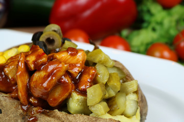 Kumpir - Traditional Turkish meal with baked potato, butter, cheese, cucumber, chicken with barbecue sauce, and hot spices