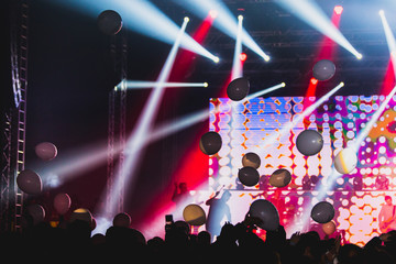 Partying crowd, stage lights and balloons at a live concert