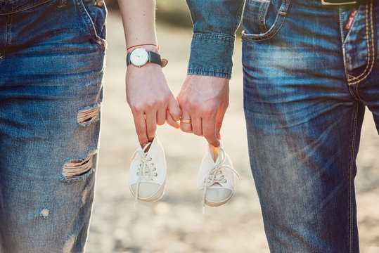 Young Pregnant Couple Holding Newborn Baby Shoes Family And Parenthood Concept